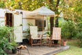 Cozy Campsite on caravan or camper van in forest. Trailer of mobile home stands in garden in camping. Royalty Free Stock Photo