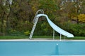 Backyard swimming pool with pool slide emptied out shutting down for winter Royalty Free Stock Photo