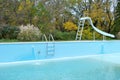 Backyard swimming pool with pool slide and ladder emptied out shutting down for winter Royalty Free Stock Photo