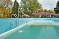 Backyard swimming pool with pool slide and ladder emptied out shutting down for winter Royalty Free Stock Photo