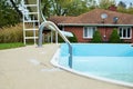 Backyard swimming pool with pool slide and ladder emptied out shutting down for winter Royalty Free Stock Photo