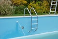 Backyard swimming pool with pool slide and ladder emptied out shutting down for winter Royalty Free Stock Photo