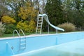 Backyard swimming pool with pool slide and ladder emptied out shutting down for winter Royalty Free Stock Photo