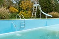 Backyard swimming pool with pool slide and ladder emptied out shutting down for winter Royalty Free Stock Photo