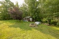 backyard tool shed and a pit on the outside of a yard. Many trees are surrounding the shed.