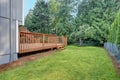 Backyard view of grey rambler house with upper and lower decks