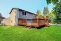 Backyard view of grey rambler house with upper and lower decks