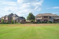 Backyard view of two-story suburban houses with solar roof panels, metal fence near large rolling hill grassy lawn of suburban Royalty Free Stock Photo