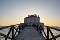 in the sunset lights, the wooden bridge that leads to the vanvitelliana house, in the fusaro lake.