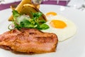 Bacon on an American breakfast plate with sunny side up eggs and french toast, close up and selective focus photo