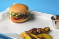 Bacon burger with beef patty, fresh tomatoes and cucumbers with sauce served on a metal tray over white background Royalty Free Stock Photo