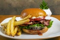 bacon cheese burger on a brioche bun with fries Royalty Free Stock Photo