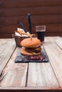 Bacon cheese burger, potato cuts and coke on table