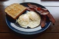 Bacon, over easy eggs, and toasted whole wheat bread breakfast Royalty Free Stock Photo