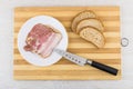 Bacon in plate, bread, kitchen knife on bamboo cutting board Royalty Free Stock Photo