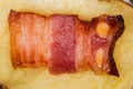 Bacon slice on baked potato half, top view close-up