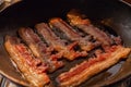 Bacon strips or rashers cooked in frying pan in the rays of sunlight Royalty Free Stock Photo