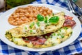 Bacon stuffed omelette with backed beans, white plate Royalty Free Stock Photo