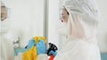 Bacteriologist or cleaning worker in biohazard protective suit washing house with chemical detergent and disinfecting