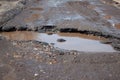 The bad asphalted road. Big pothole filled with water. Dangerous destroyed roadbed. Royalty Free Stock Photo