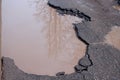 The bad asphalted road. Big pothole filled with water. Dangerous destroyed roadbed. Royalty Free Stock Photo