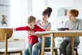 Bad behaving cute boy trying to run during therapy session with his mother and teacher