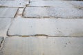 Bad concrete dirty road of blocks and slabs with seams and cracks requiring repair at the construction site of buildings houses Royalty Free Stock Photo