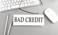 BAD CREDIT text on paper with keyboard on grey background