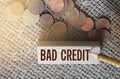 Bad credit text on wooden block and coins on burlap canvas. Crisis times unpaid loand and credits financial business concept