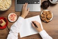 Bad eating habits. Woman surrounded by different snacks working at wooden table, top view