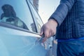 Bad guy scratching the car door with a screwdriver in the parking lot on the street. Damage of property from revenge for treason