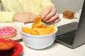 Bad habits. Woman eating tortilla chips at white office table, closeup