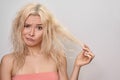 Beautiful woman with messed up hair. Unhappy grimacing face. Blond bleaching hairstyle with problem brittle hair Royalty Free Stock Photo