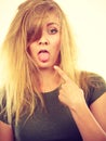 Sad blonde woman with messy hair pointing tongue Royalty Free Stock Photo