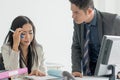 Bad leadership management. Asian boss / manager shouting to female employee at desk in office and upset with her error Royalty Free Stock Photo