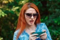 Bad news. Closeup young unhappy frustrated disappointed beautiful red head woman girl lady looking at  mobile phone isolated green Royalty Free Stock Photo