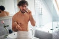 Bad news in the morning. Young caucasian handsome guy receiving bad news on his cell phone while brushing his teeth in the
