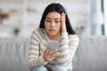 Bad News. Upset Asian Female Holding Smartphone, Looking At Screen With Worry