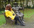 A woman sitting beside a bronze statue