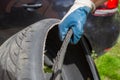 Bad quality of wheels. the hand of the master in a blue glove holds the torn tire. on the background black car in blur