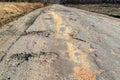 Bad road, cracked asphalt with potholes and big holes. Potholes on the road with stones on the asphalt. The asphalt surface is Royalty Free Stock Photo
