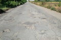 Bad road, cracked asphalt with potholes and big holes. Potholes on the road with stones on the asphalt. The asphalt surface is Royalty Free Stock Photo