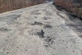 Bad road, cracked asphalt with potholes and big holes. Potholes on the road with stones on the asphalt. The asphalt surface is Royalty Free Stock Photo