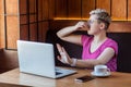 Bad smell. Portrait of unhappy confused young woman with short hair in pink t-shirt and eyeglasses is sitting in cafe, covering