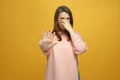 Bad smell. Young girl pinch nose with hand to avoid disgusting odor, frowning, showing stop gesture on yellow background
