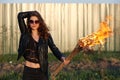The bad woman in sunglasses and a black jacket holding a torch Outdoors