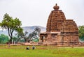 Two women care for grass in front of a Bhuthnath temple carved w