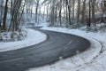 badly damage road with a steep s-curve in winter forest