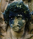 A badly damaged female face carved from stone
