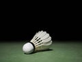 Badminton ball or shuttlecock located on the green ground with a black background. Concepts of victory or strength in training.